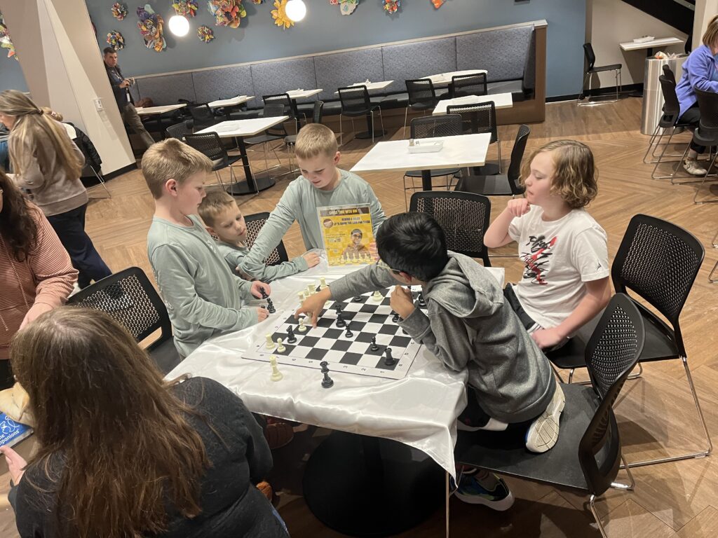 A chess lesson around a table with several children